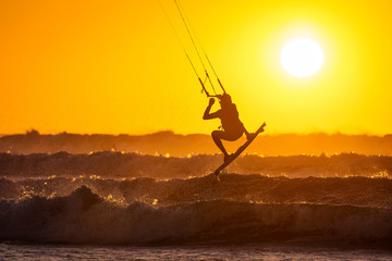 Silhoutte of kitesurfers enjoying big waves at sunset in Essaouira, Morocco. Beautiful landscape in...