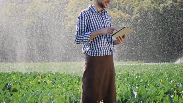 Farmer using digital tablet during monitoring his plantation.