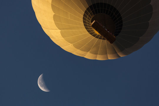 View from bellow a colorful hot air ballloon near the moon with beautiful blue sky in background