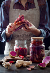 Cabbage kimchi in glass jar. Woman preparing purple cabbage and watermelon radish kimchi. Fermented...