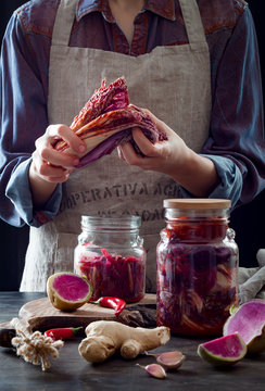 Cabbage kimchi in glass jar. Woman preparing purple cabbage and watermelon radish kimchi. Fermented and vegetarian probiotic food for gut health