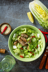 Diet menu. Healthy salad with Chinese cabbage, chicken, sesame and chili pepper on a dark stone table. Top view flat lay background. Copy space.