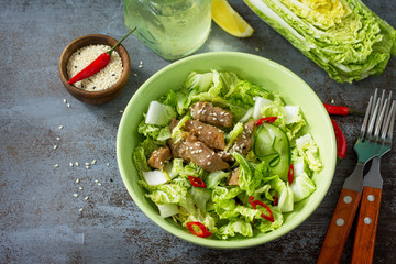 Diet menu, Vegan food. Healthy salad with Chinese cabbage, chicken, sesame and chili pepper on a dark stone table. Copy space.