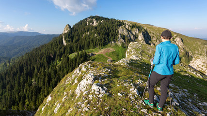 Naklejka na ściany i meble Girl hiking through the Buila Vanturarita national park in Romania on a sunny summer day