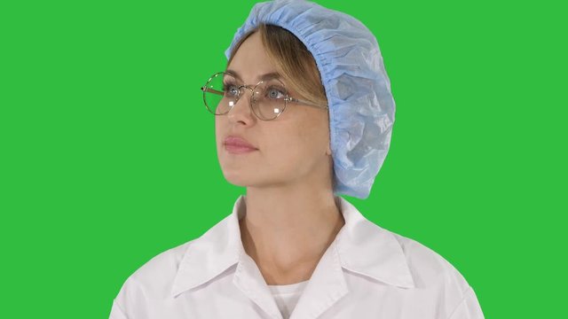 Woman doctor in glasses and hat walking and looking around on a Green Screen, Chroma Key.