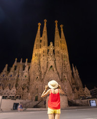 Young woman tourist in front of the famous Sagrada Familia landmark at evening time in Barcelona