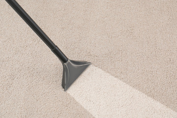 Removing dirt from carpet with vacuum cleaner in room