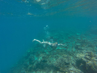 Fototapeta na wymiar Young girl diving in a blue clean water