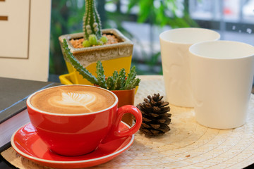 Latte art in white cup on wooden table in morning.