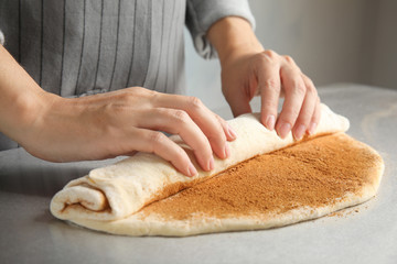 Obraz na płótnie Canvas Woman making cinnamon rolls at table, closeup