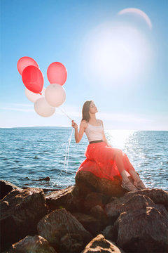 Pretty girl with many colored balloons in hand