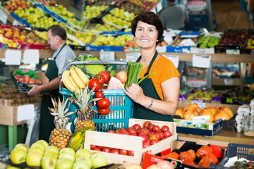 Obraz premium Woman seller demonstrating basket with vegetables and fruits