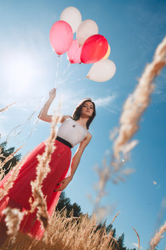 Pretty girl with many colored balloons in hand