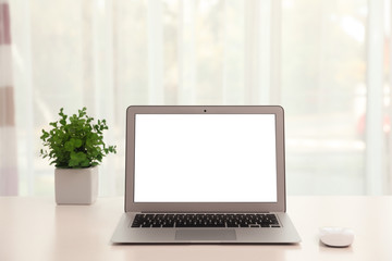 Laptop with computer mouse on table indoors. Space for text