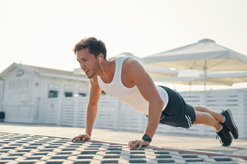 Picture of a young athletic man doing push ups, leg over leg lis © diignat