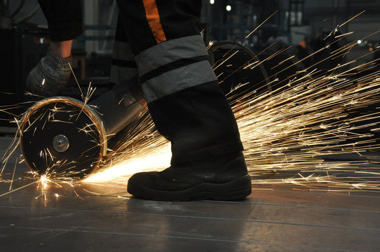Worker at the factory cuts metal. sparks fly