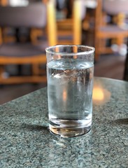 Medium close up of a glass of ice cold water  on a table top