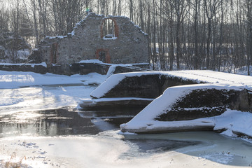 Ancient abandoned water mill surrounded by beautiful nature. House built of stone. The land is white, snowy in the winter