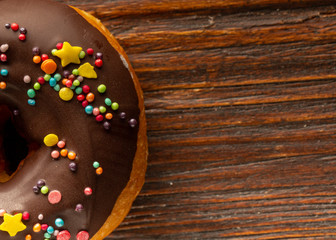 Fresh donut served on the old wooden table with a clearly visible texture