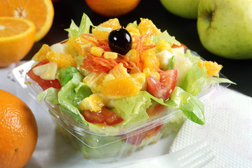 Ensalada para llevar con lechuga, tomate, maiz , naranja, manzana, zanahoria y una aceituna.