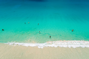 Obraz premium Aerial view of sandy beach with tourists swimming in beautiful clear sea water