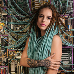 Portrait of a girl with a tattoo and dreadlocks tied to the motherboard. Internet addiction concept.