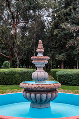 Long shot of a beautiful fountain in a public park surrounded by trees
