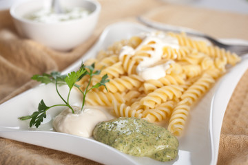 Pasta in white plate, parsley, bowl with mayonnaise sauce