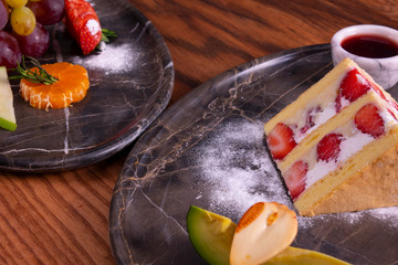 Strawberry cake and fruit plate on wooden table
