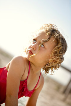 Young blond girl making a grumpy face at someone behind her.