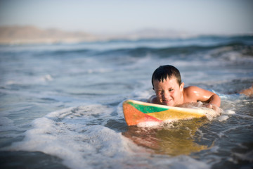 Young boy lying on a surfboard in the ocean.