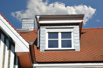 Mit Naturschiefer verschindelte Schleppgaube an einem renovierten Altbauhaus