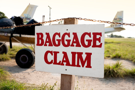 Baggage claim sign on the fence of a rural airstrip.