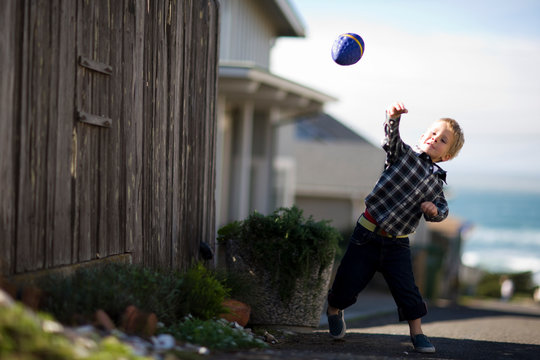 Young boy playing outside with a toy football.
