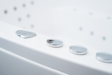 Hydromassage bathtub control buttons in bathroom.