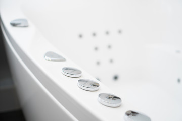 Hydromassage bathtub control buttons in bathroom.