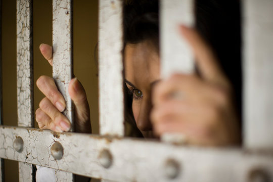 Mid-adult business woman behind bars in a derelict building.
