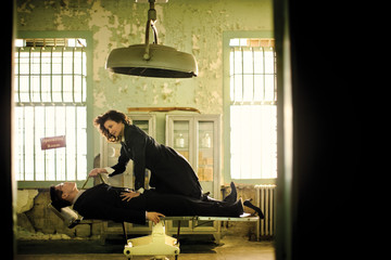 Mid-adult woman on top of a man in an operating room.