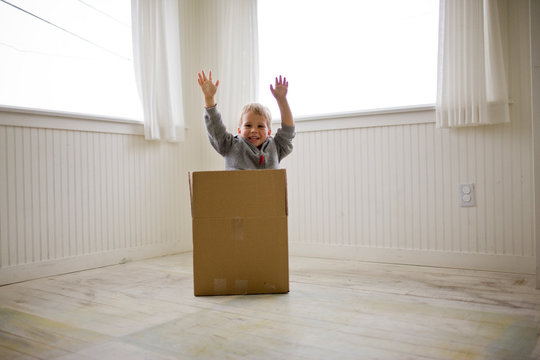 Boy jumping out of box in house