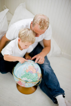 Father pointing out places on a globe to his son