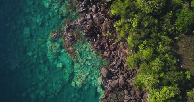 Aerial view of a Tropical paradise coastline over a Caribbean island with Turquoise water and small waves hitting the rocks