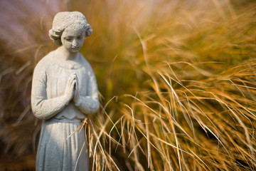 Serene stone statue next to a grass bush.