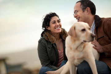 Portrait of a happy mid adult couple with their golden labrador.