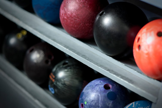 Several bowling balls lined up in a storage rack.