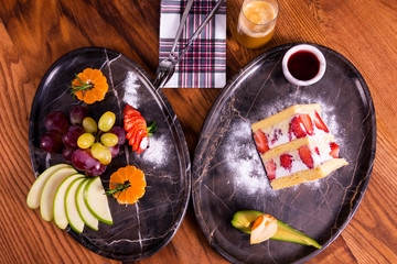 Strawberry cake, coffee and fruit plate on wooden table