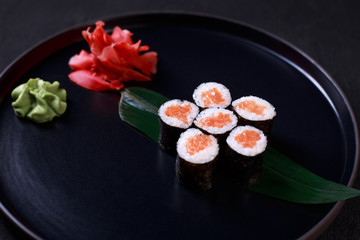 restaurant menu, delicious traditional seafood. maki roll with salmon, served on black plate, close up