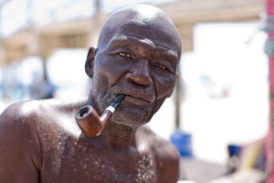 Portrait of a bald senior man smoking a pipe outdoors.