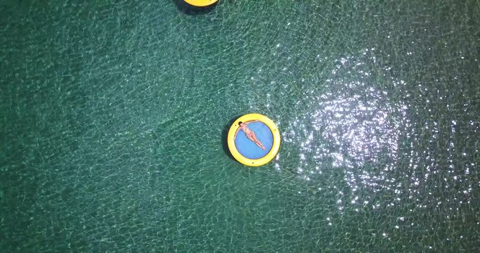 Drone over a girl in bikini relaxing on a water hammock on a Tropical paradise beach setting in the Caribbean island of St Lucia