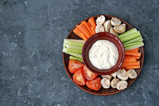 Vegetable Tray With A Ranch Dip On A Dark Background. Raw Vegetable Mix Includes Sliced Mushrooms, Carrots, Celery, Tomatoes.