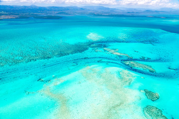 Aerial view of idyllic azure turquoise blue lagoon of West Coast barrier reef, with mountains far...